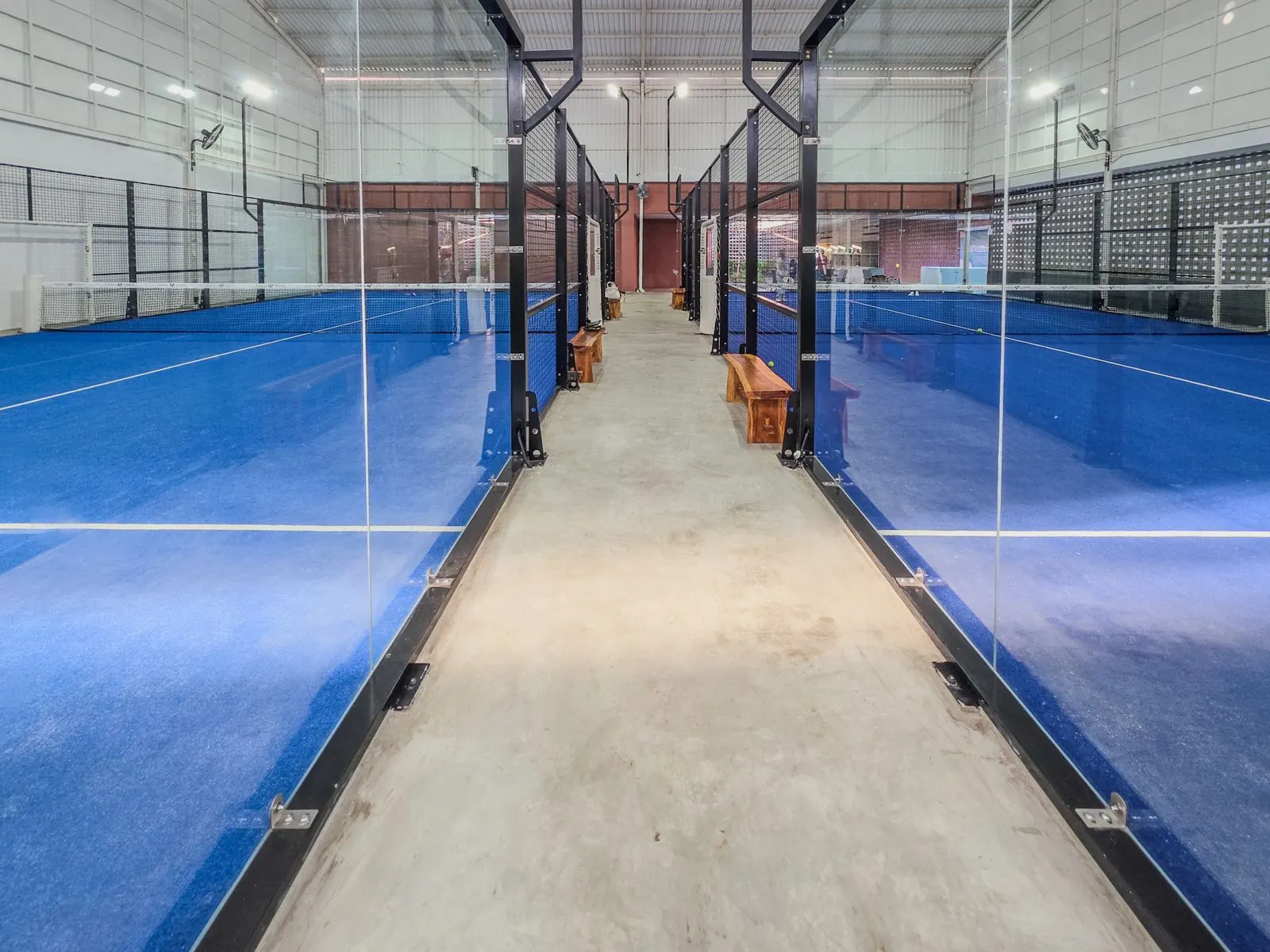 Blue padel courts enclosed in glass and steel