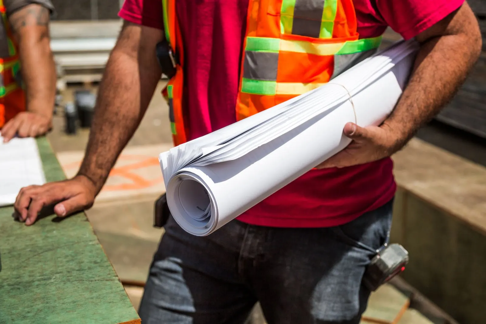 Worker carrying construction drawings on site